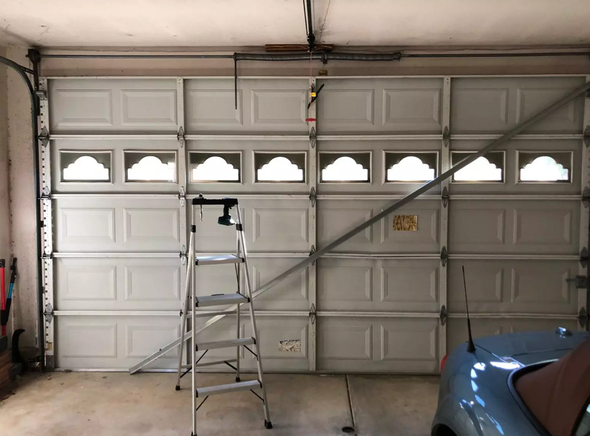 a technician repairing a residential garage door under the bright Florida sun, representing local garage door repair services available in Weston, FL.